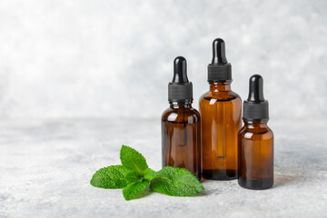 Essential oil mint on a wooden background. Peppermint essential oil with fresh mint leaves. A bottle of aromatherapy oil. Mint extract. The concept of natural cosmetics, spa care. copy space