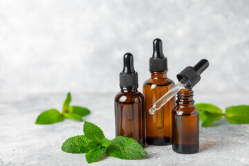 Essential oil mint on a wooden background. Peppermint essential oil with fresh mint leaves. A bottle of aromatherapy oil. Mint extract. The concept of natural cosmetics, spa care. copy space