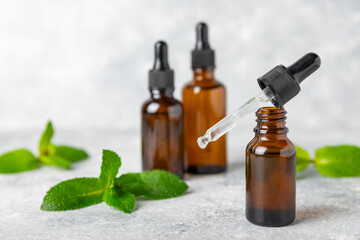 Essential oil mint on a wooden background. Peppermint essential oil with fresh mint leaves. A bottle of aromatherapy oil. Mint extract. The concept of natural cosmetics, spa care. copy space
