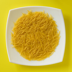 FIDEOS SOBRE UN PLATO EN FONDO AMARILLO