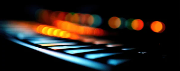 Musical keys illuminated by colorful lights during a nighttime recording session © iwaart