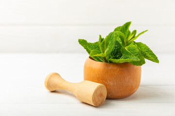 Fresh mint with mortar and pestle on wooden background. Melissa leaves. Healing herbs green mint...