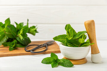 Fresh mint with mortar and pestle on wooden background. Melissa leaves. Healing herbs green mint...