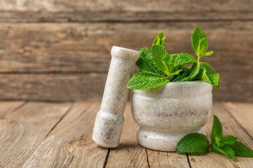 Fresh mint with mortar and pestle on wooden background. Melissa leaves. Healing herbs green mint leaves in mortar for medicine.Space for text. Copy space.
