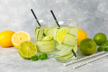 Cucumber water with lemon, lime and mint on a wooden table. Water infused with sliced ​​cucumber in a drinking glass. Tonic refreshing drink. Cucumber lemonade.Summer natural cooling drink.Copy space