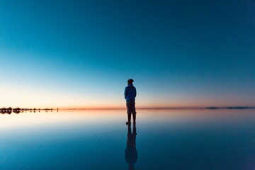 ボリビアの早朝のウユニ塩湖に立つ男性のシルエット