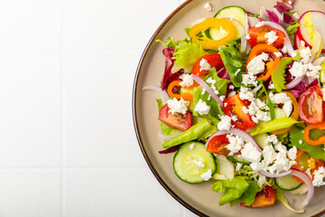Cucumber salad on a wooden background.Homemade salad with fresh vegetables, cucumber, tomato, sweet pepper and lettuce in a plate.Vegetarian spring salad.Vegetarian diet.Healthy eating.Space for text