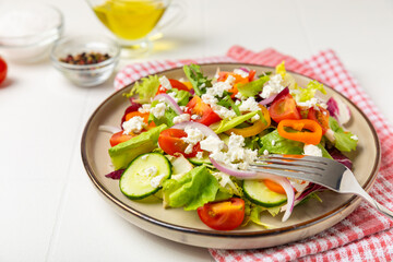 Cucumber salad on a wooden background.Homemade salad with fresh vegetables, cucumber, tomato, sweet pepper and lettuce in a plate.Vegetarian spring salad.Vegetarian diet.Healthy eating.Space for text
