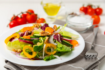 Cucumber salad on a wooden background.Homemade salad with fresh vegetables, cucumber, tomato, sweet pepper and lettuce in a plate.Vegetarian spring salad.Vegetarian diet.Healthy eating.Space for text