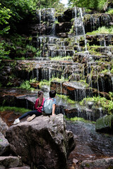 Young hikers admiring cascading waterfall in lush forest