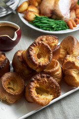 Traditional Yorkshire puddings on a table with other food in background. 