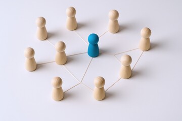 Obraz premium Wooden Figures Representing Network Connection, Leadership, and Teamwork with a Blue Figure in the Center