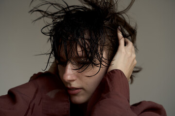 Young person with wet disheveled hair in burgundy sweater showing authentic emotional moment