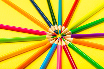 Colored pencils on a bright colored background. Equipment for coloring. Stationery for...