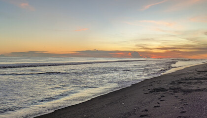 Tropical beach sunset with golden sky, gentle waves and serene ocean horizon view