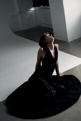 Graceful woman in black dress positioned elegantly against white geometric studio backdrop