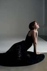 Artistic studio portrait of woman in flowing black garment with dramatic side lighting