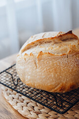 Homemade sourdough bread cooling on a rack on a rustic wooden table