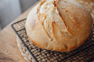 Fresh homemade sourdough bread cooling on a rack over a rustic wooden table