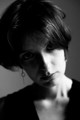 Striking black and white close-up portrait of woman with short hair in dramatic chiaroscuro lighting style