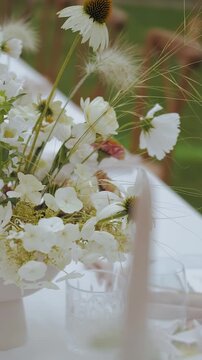 Flowers in a vase on a dining table, close-up of a bouquet of pastel fresh flowers outdoors, flowers swaying in the wind. Flower arrangement on the table, slow motion. Wedding decor.