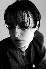 Moody close-up portrait of young woman with tousled dark hair in soft natural lighting emphasizing...