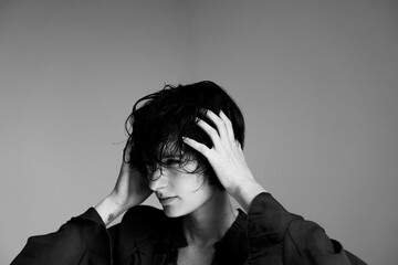 Monochrome studio portrait of woman in dark blazer covering face with hand in emotional moment