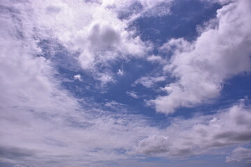 A beautiful blue sky filled with fluffy white cumulus and wispy cirrus clouds on a bright sunny day.