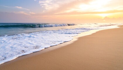 Obraz premium Sandy beach at sunrise with ocean waves.
