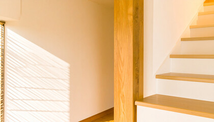 Wooden stairway illuminated by sunlight: showcasing a light, airy space with warm, inviting tones, the staircase guides the eye upwards, evoking a sense of tranquility and open concept living. 