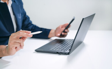 Business man  using a laptop and a cell phone at the same time.