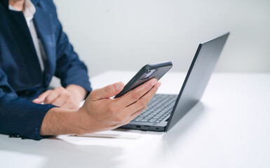 Business man  using a laptop and a cell phone at the same time.