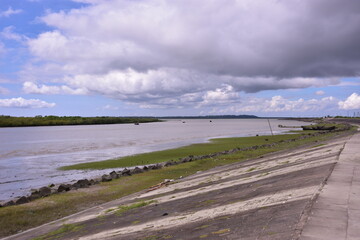 A scenic view from the riverfront promenade in Cox's Bazar, Bangladesh, looking over the Bakkhali River estuary on a cloudy monsoon day.