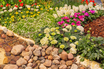 Vibrant flower garden with colorful blooms, lush greenery, and decorative stones creating a serene landscape