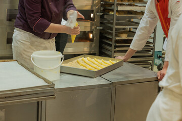 Baking process in a commercial kitchen with pastry chefs preparing dough on stainless steel table