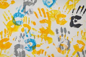 Bright handprints create a colorful mural on a white canvas in a vibrant community art project © mira_y