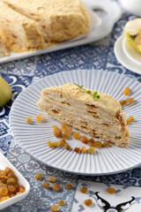 Delicious dessert slice featuring layered cake with cream and raisins served on decorative plate in bright setting