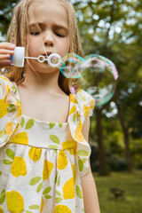 Child Blowing Bubbles in a Green Park Setting.