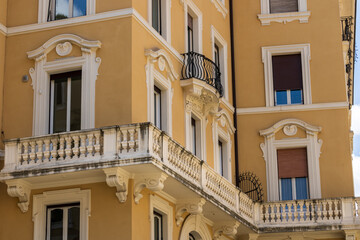 windows and a balcony on a yellow building overlooking a Roman street, Golden walls, quiet windows, and a balcony with a view