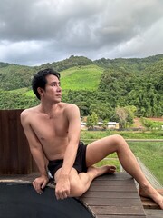 Handsome man relaxing on a holiday at a balcony with a beautiful mountain view.