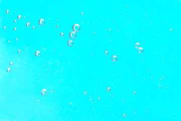 Macro image of small air bubbles suspended in bright turquoise liquid, creating a fresh, clean, and...