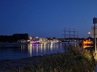 Peaceful Night View of a Harbor with a Tall Ship and Water Reflections