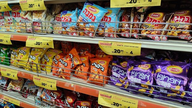 Rishon Lezion, Israel - 5 Aug 2025. Shelves stocked with Osem Bamba, Bissli, and chips, with price tags. Rising prices, inflation, economic crisis, taxes and price increase in Israel in shekels.