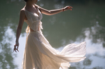 Graceful woman dancing near tranquil water.