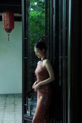 Elegant woman in traditional dress by a glass door.