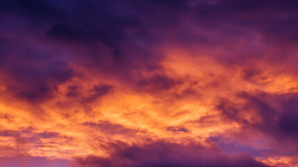 Obraz premium Dramatic sunrise with gradient orange and purple clouds, creating a panoramic abstract sky view.