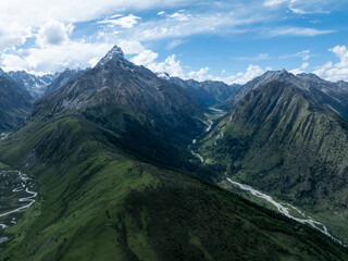Aerial view of beautiful high altitude snow capped mountains and forest grassland landscape in China