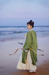 Young woman in traditional clothing by the beach.