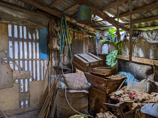 Messy interior of an old countryside shed filled with tools, hoses, wooden boxes, and rural...