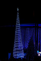 Christmas and New Year interior decoration with background, pine tree decorated with beautiful garlands of lights.